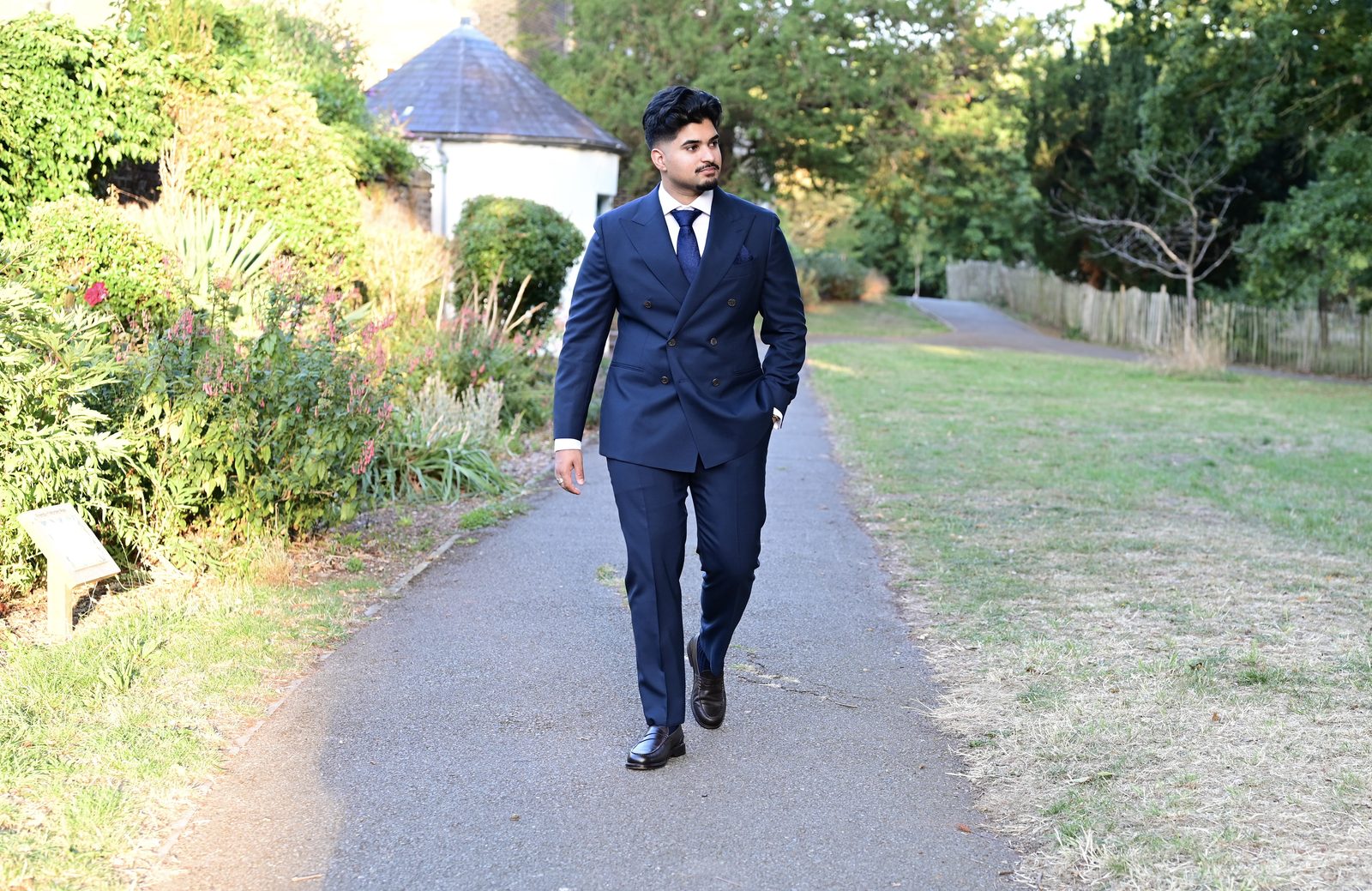 Nehan Khan, credit and personal finance educator, walking outdoors in a navy suit